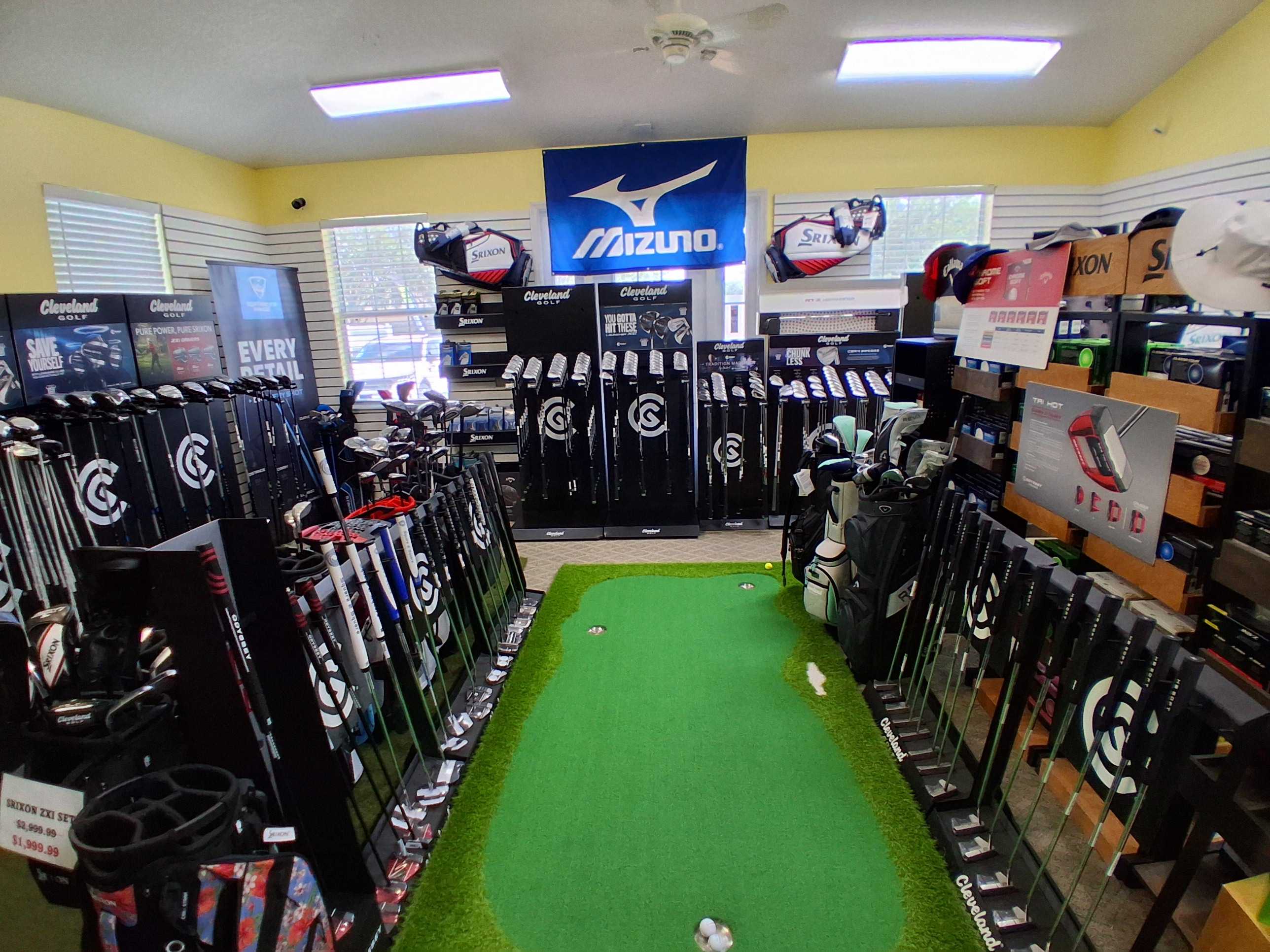 Full club selection on the Oxford Golf Academy pro shop floor with practice putting green
