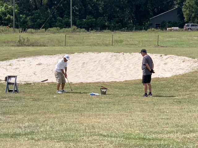 Instructor coaching a student during a bunker lesson at Oxford Golf Academy