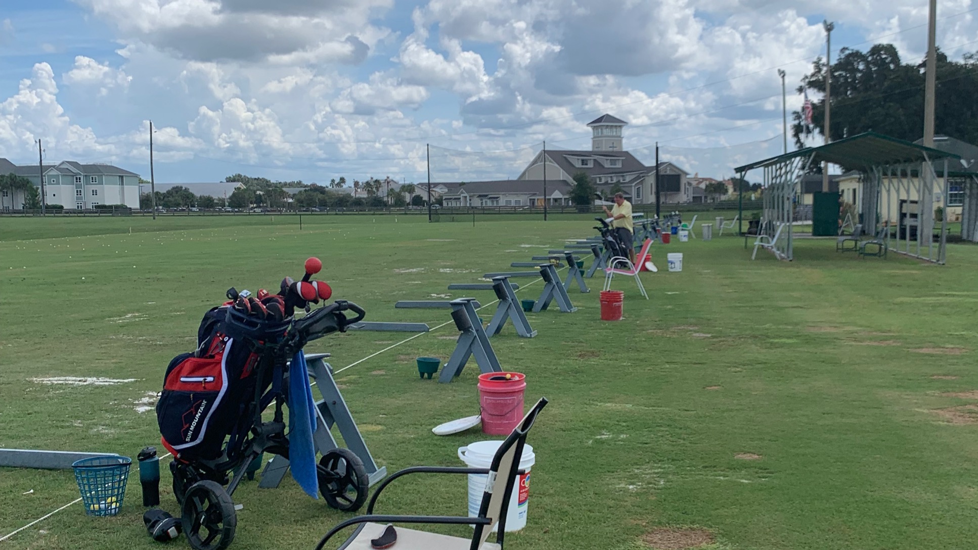 Golfer at the Oxford Golf Academy driving range with bags and buckets