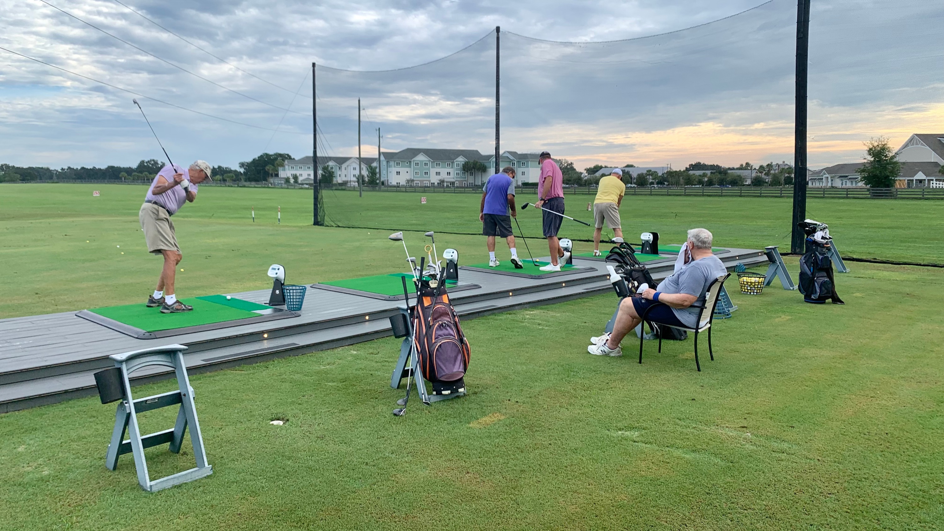 Group of golfers gathering at the Oxford Golf Academy range in the evening